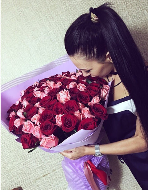 Woman leaning over a large bouquet of red and pink roses