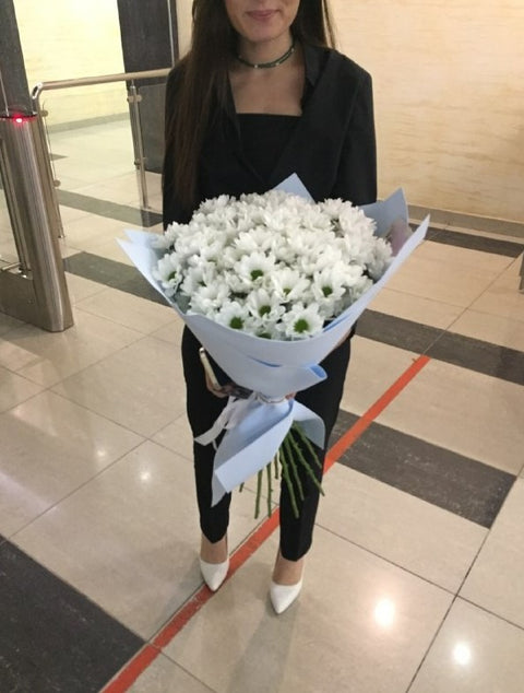 Woman holding white flowers wrapped in pale blue paper