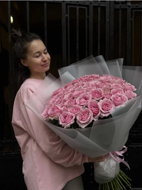 Woman holding a large bouquet of soft pink roses