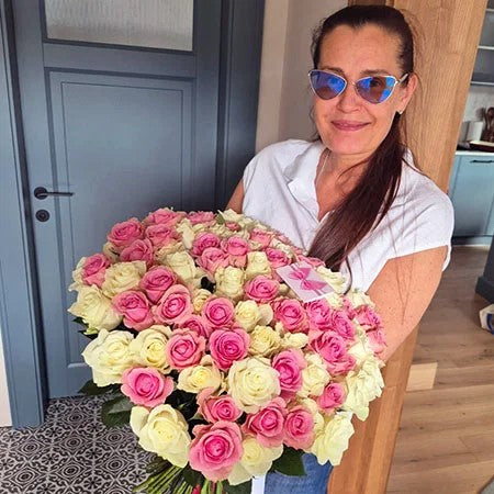 Woman in sunglasses holding pink and cream roses