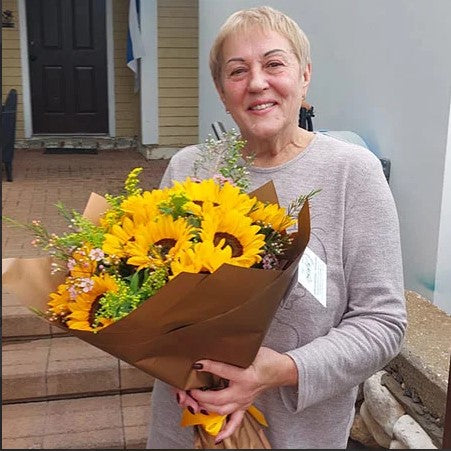 Woman holding a bouquet of sunflowers and orange flowers