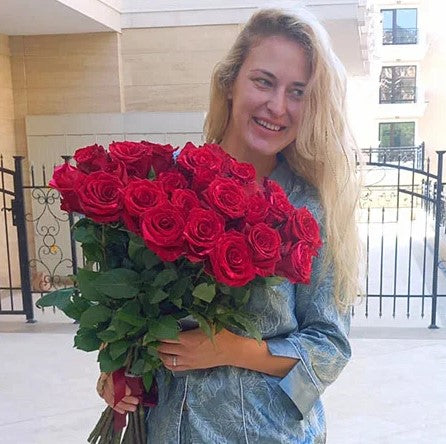 Woman smiling with a large bouquet of red roses