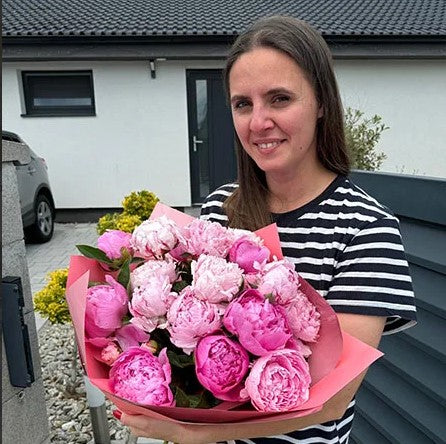 Woman holding a bouquet of pink peonies outdoors
