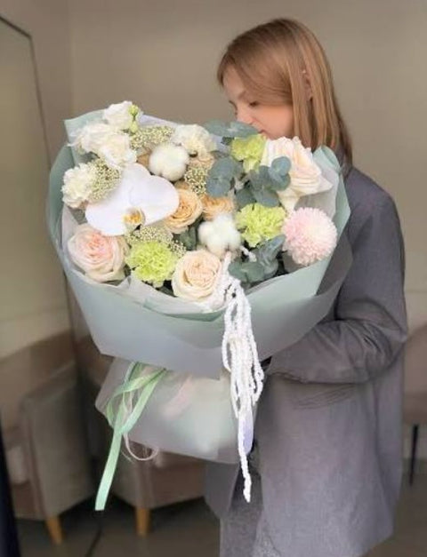Woman looking at a bouquet with a white orchid and pale roses