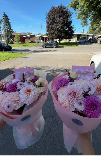 Two pink and white flower bouquets held outdoors
