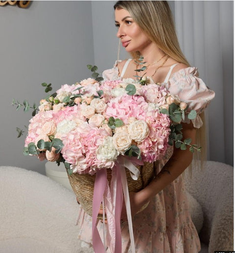 Woman holding a large pink and cream floral arrangement
