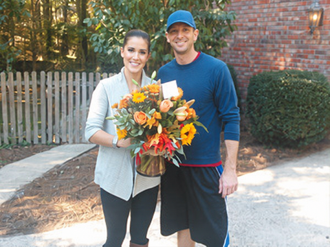 Couple holding an orange flower arrangement outdoors