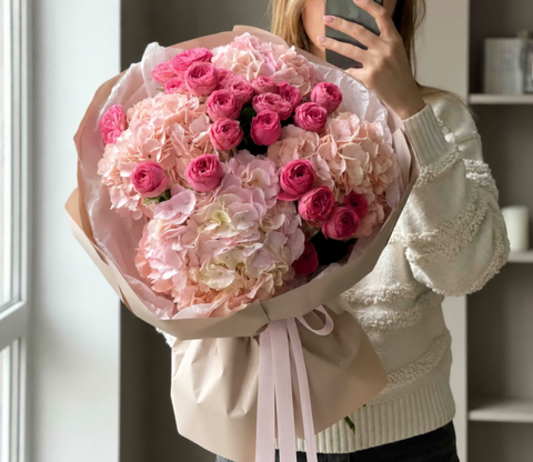 Woman holding a bouquet of pink roses and hydrangeas