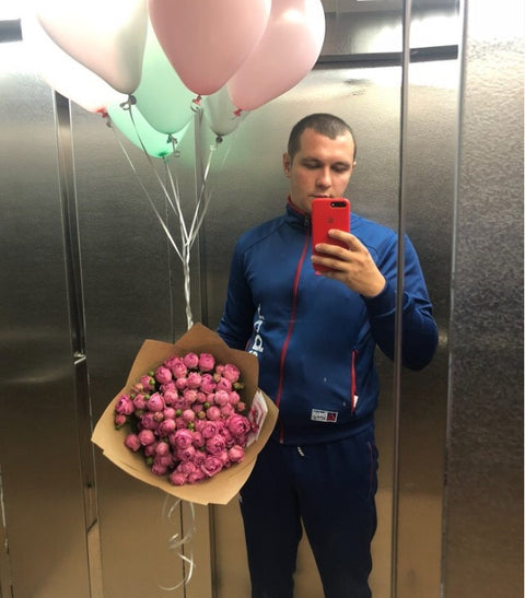 Man with pink roses and balloons in an elevator