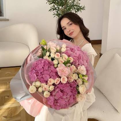Woman holding a bouquet of pink and white flowers on a sofa