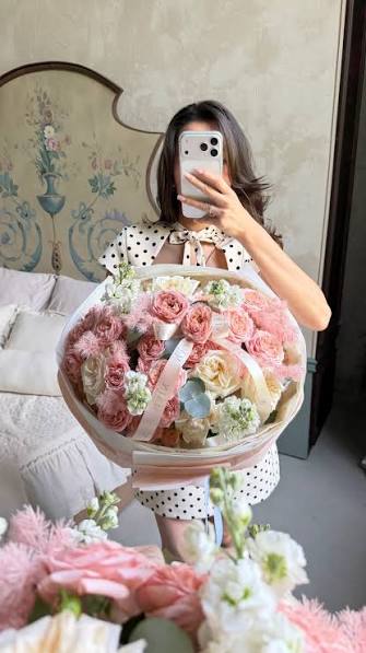 Woman taking a mirror selfie with a pastel flower arrangement