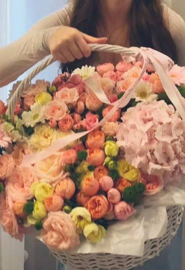 Woman holding a large basket of peach and pink flowers