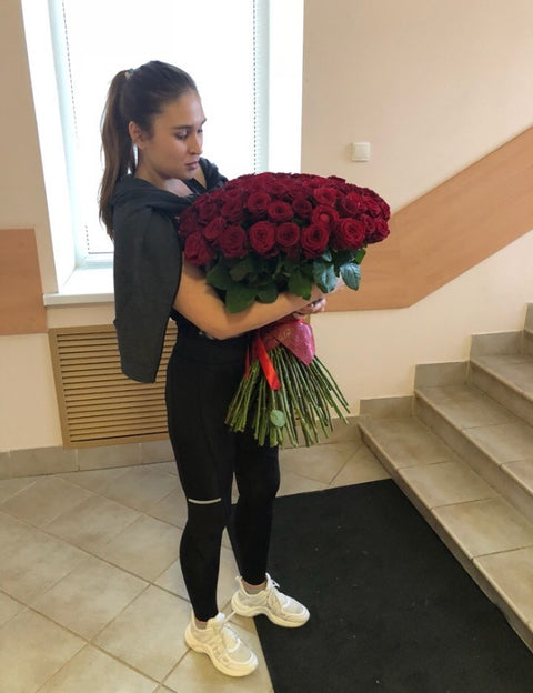 Woman carrying a large bouquet of dark red roses