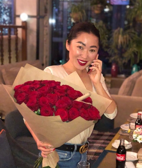 Woman holding a bouquet of red roses in a restaurant